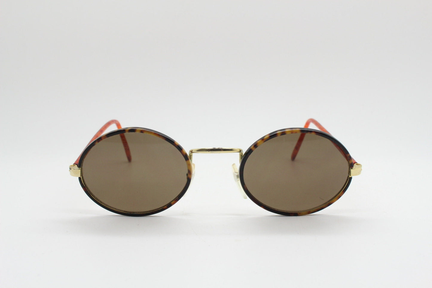 90s vintage oval sunglasses. Handsome honey tortoise and blazing amber arm combo on a slender metal frame. NOS