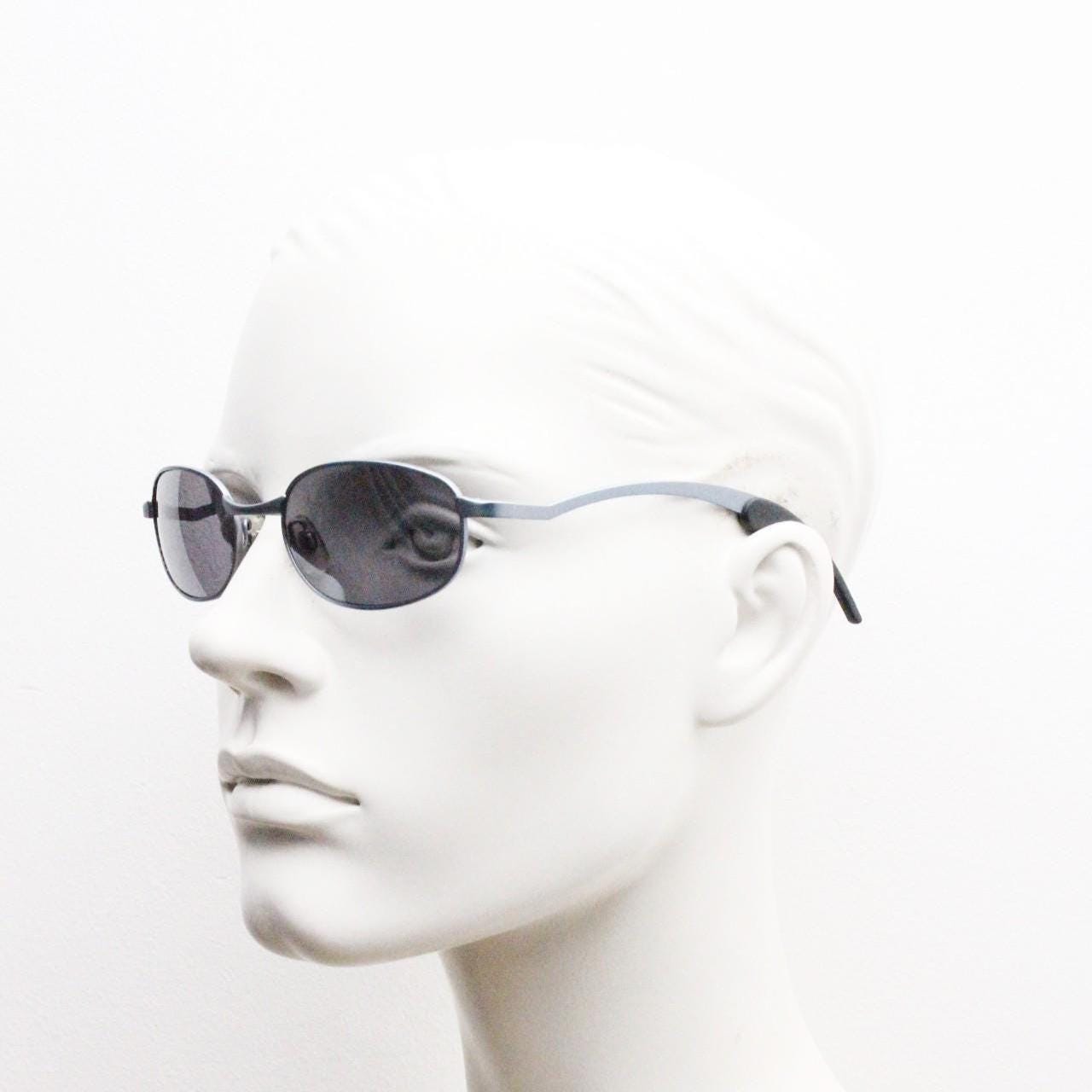 90s vintage oval small bug eye sunglasses. Curved blue satin finish solid metal frame with stylised arched arms and rubber ends. Unused NOS