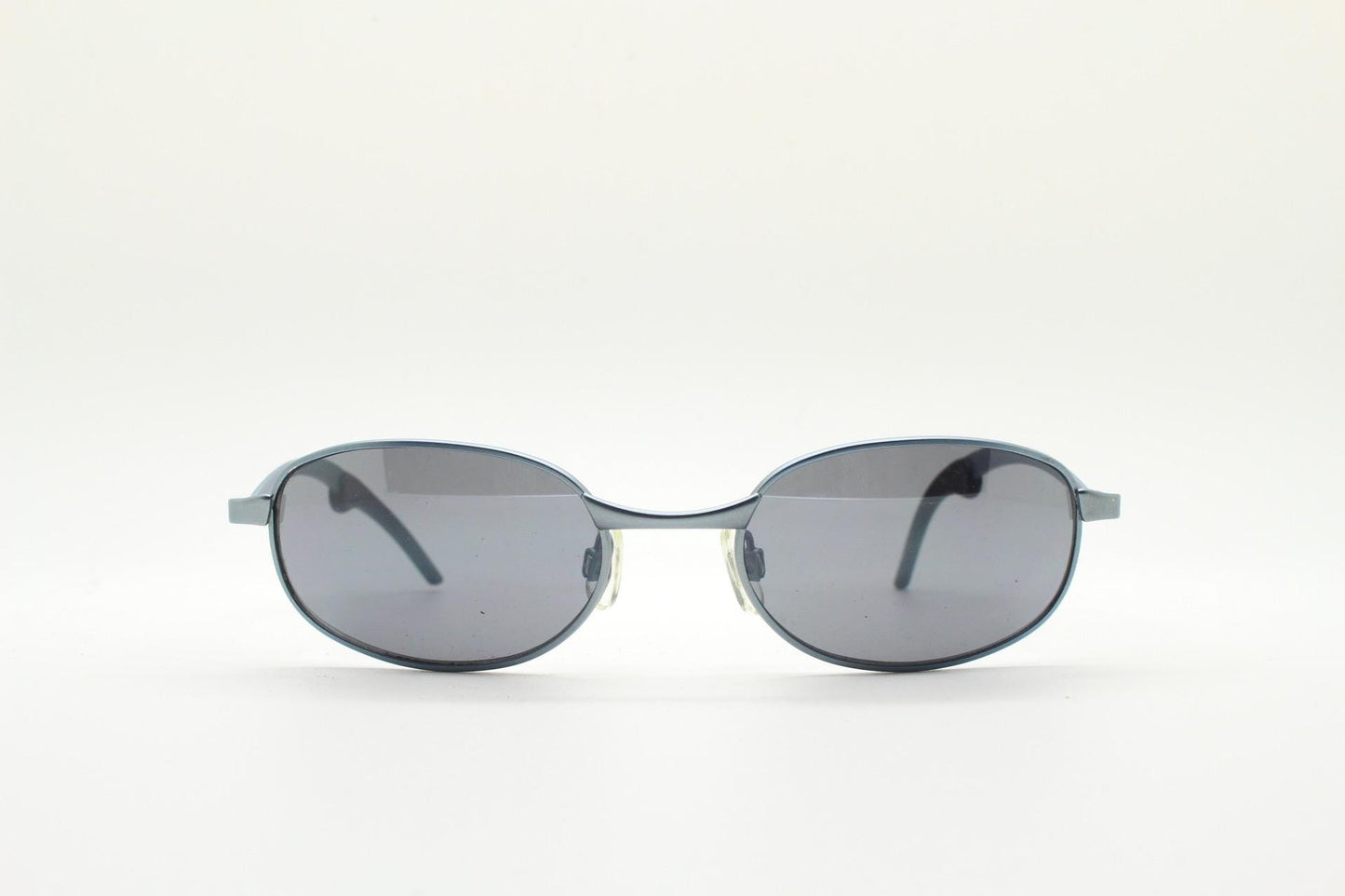 90s vintage oval small bug eye sunglasses. Curved blue satin finish solid metal frame with stylised arched arms and rubber ends. Unused NOS