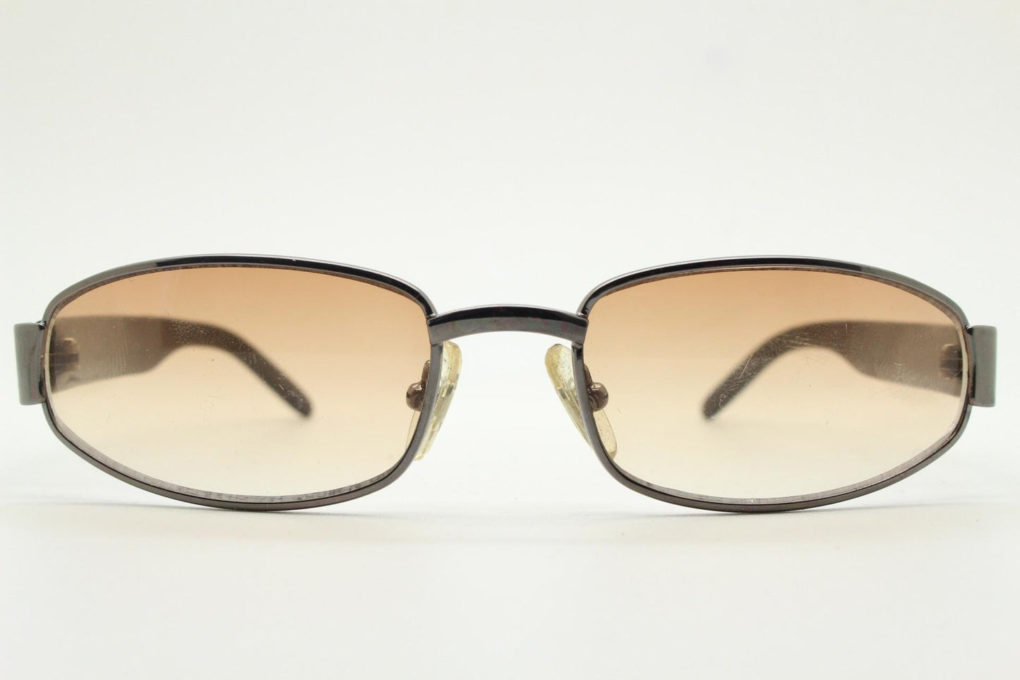 90s vintage oval sunglasses small bug eye with light tone lenses. Satin finish brown metal frame with black arms. 2000's. NOS
