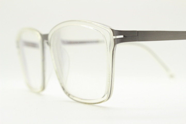 Modo rectangular eye glasses made in Japan. Matt grey titanium optical frame encasing transparent crystal acetate front. Prescription RX