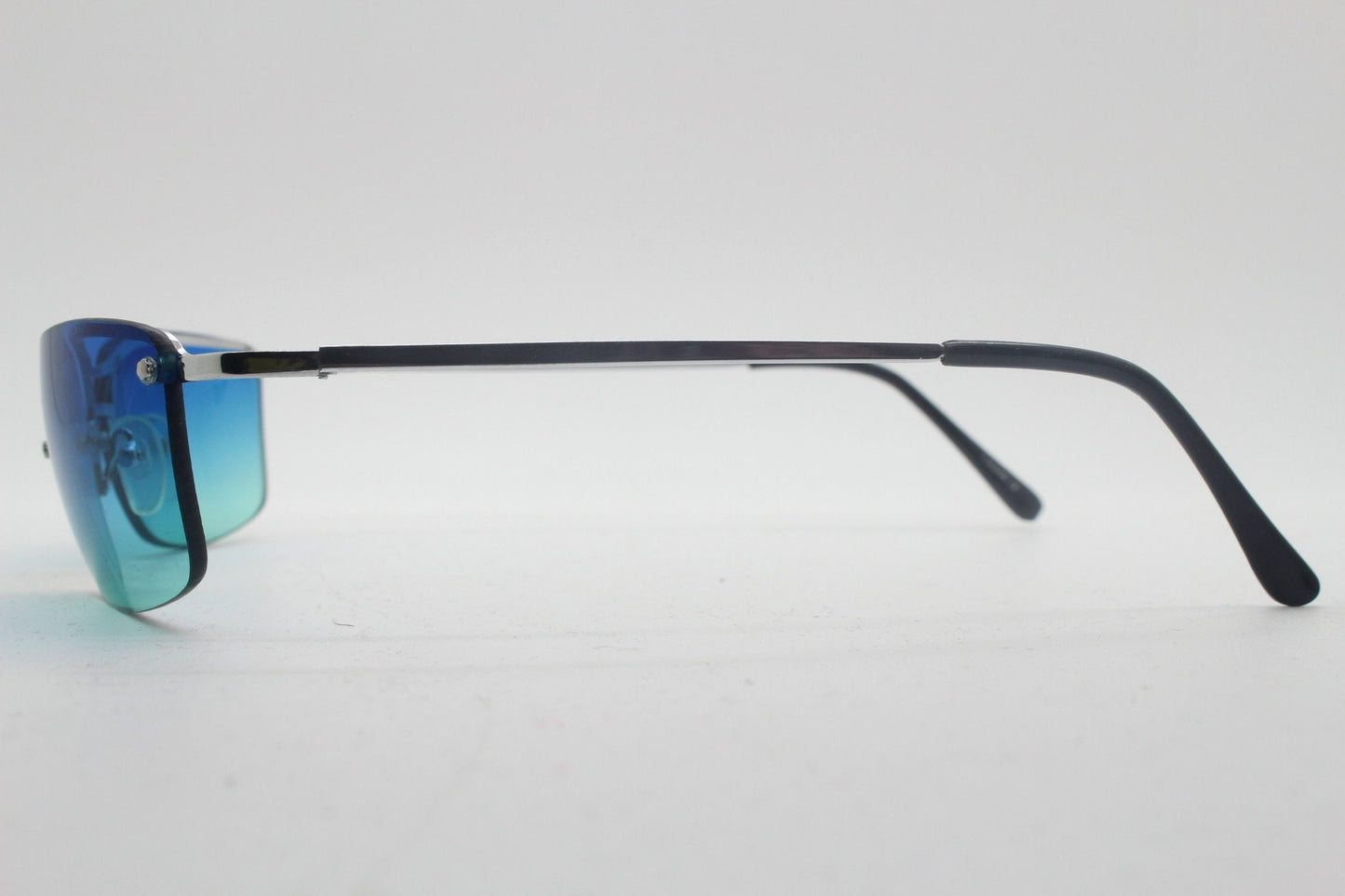 Y2K vintage visor sunglasses. Half frame wraparound shield design with light tone graduating turquoise to aquamarine lens. 2000's. 90s. NOS