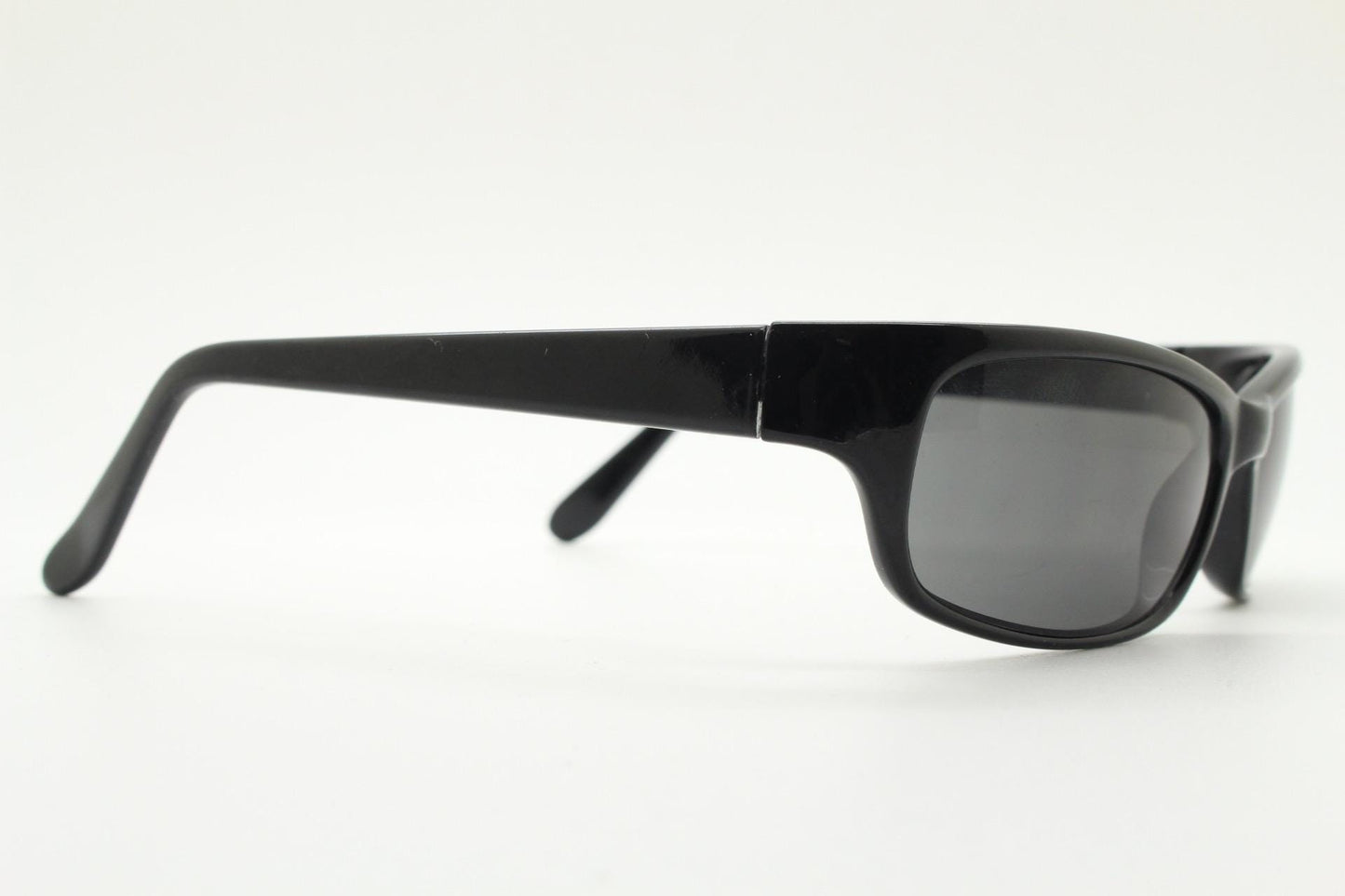 90s vintage curved wraparound sunglasses. Aerodynamic low profile plain black gloss curved cat eye frame. Minimal shield design. NOS