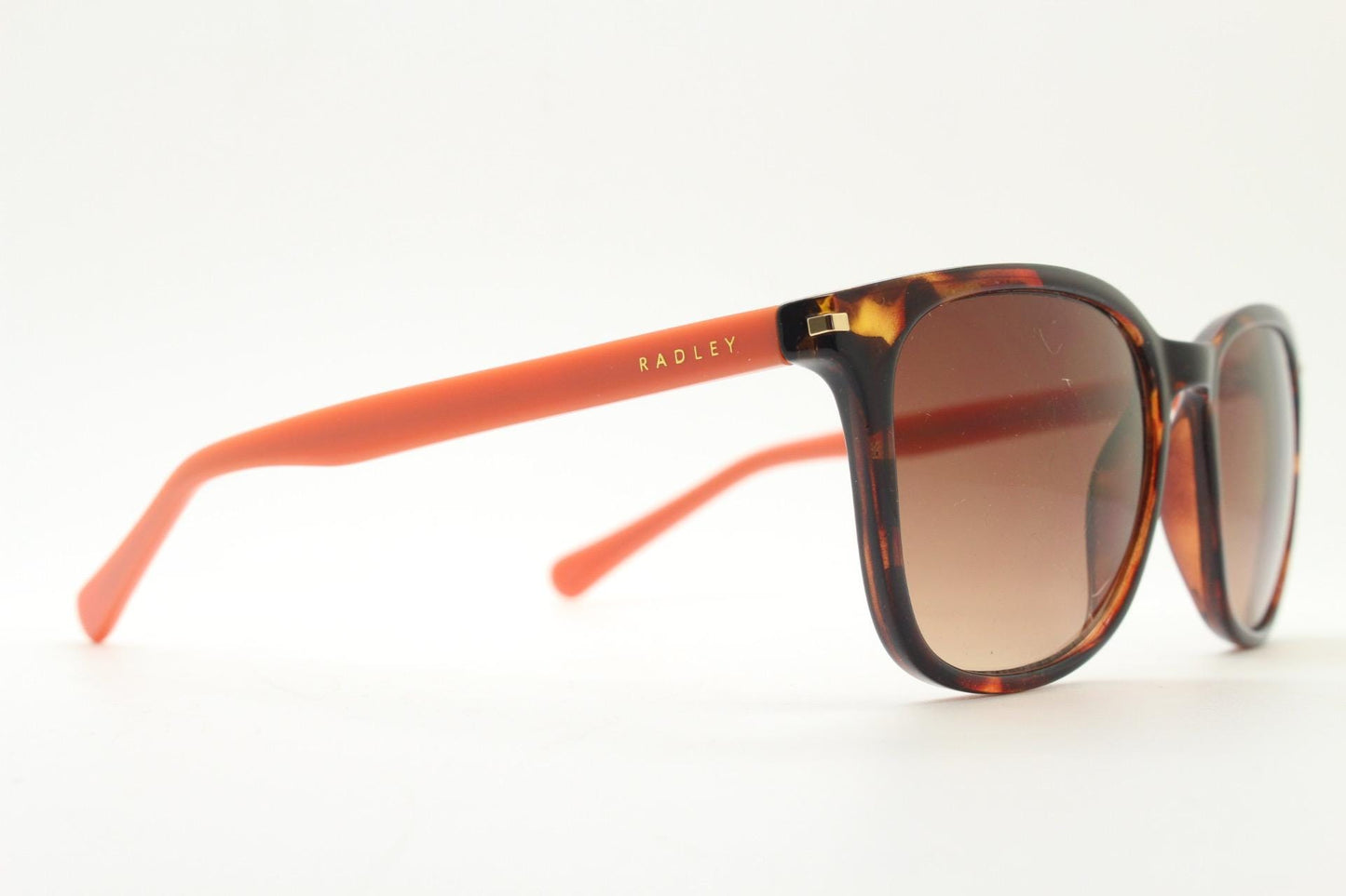 Modified wayfarer design sunglasses by Radley. Tortoise front with bright orange arms and Havana brown lenses. Vintage. Unused NOS