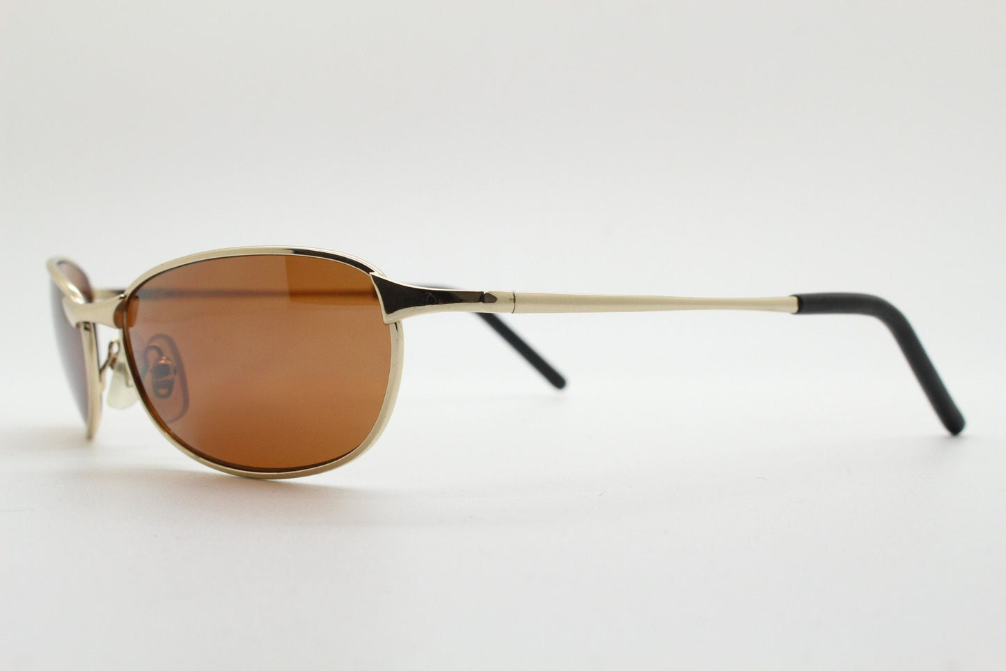 90s vintage curved angular oval sunglasses. Solid metal small bug eye frame in gold chrome with mid tone brown lenses. 2000's. Y2K NOS