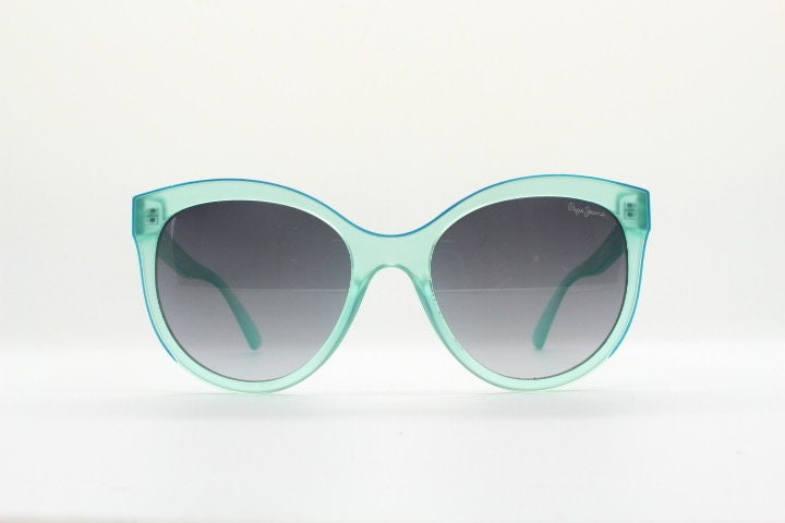 Pepe Jeans big cat eye sunglasses. Transparent chunky aquamarine frame with contrasting black graduating lenses. Womens vintage cateye
