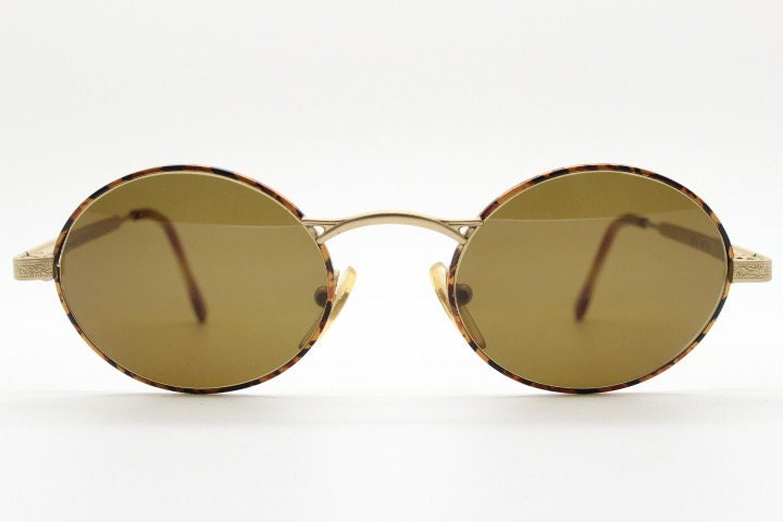 Armandos 90s vintage oval sunglasses made in Italy. Enamelled honey tortoise front with ornate tooled metal arm patterns. NOS