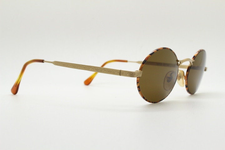 Armandos 90s vintage oval sunglasses made in Italy. Enamelled honey tortoise front with ornate tooled metal arm patterns. NOS