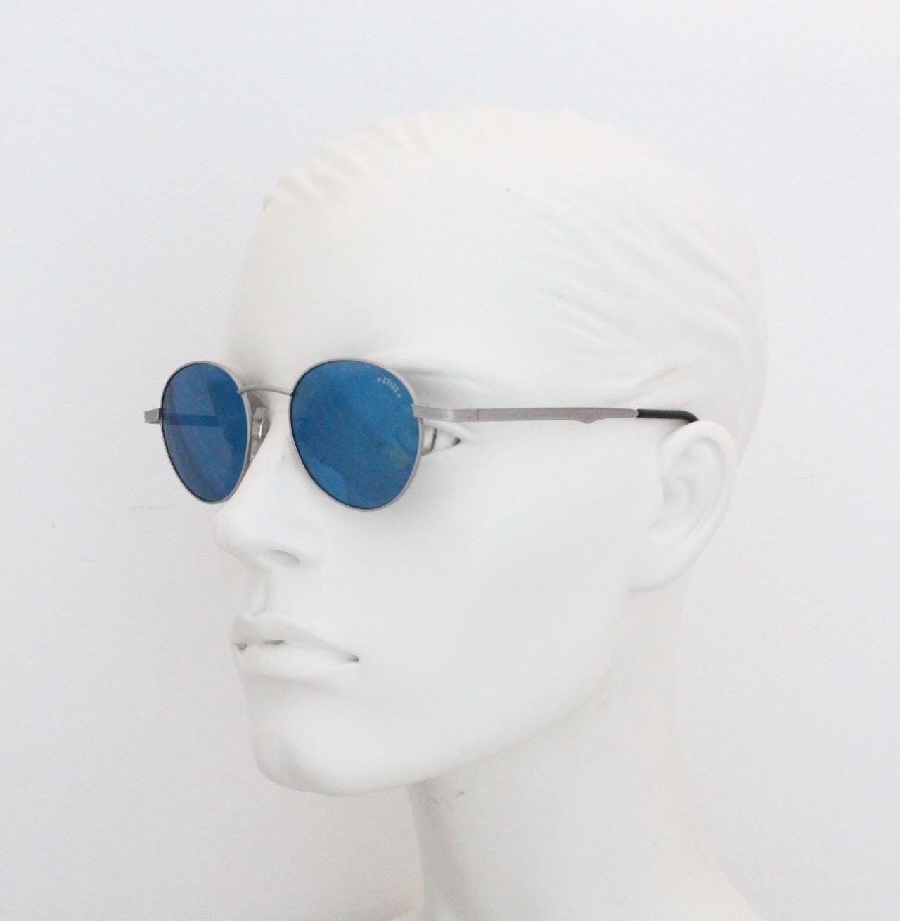Sting 90s vintage oval sunglasses made in Italy. Minimal grey aluminium look in slightly small proportions with blue mirror lenses
