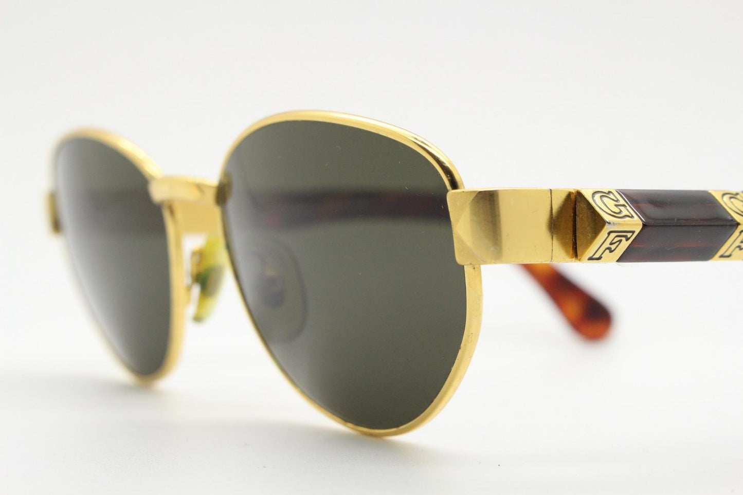 Gianfranco Ferre oval sunglasses made in Italy. Gold frame with triangular tortoise acetate arms and green lenses. 90s vintage GFF