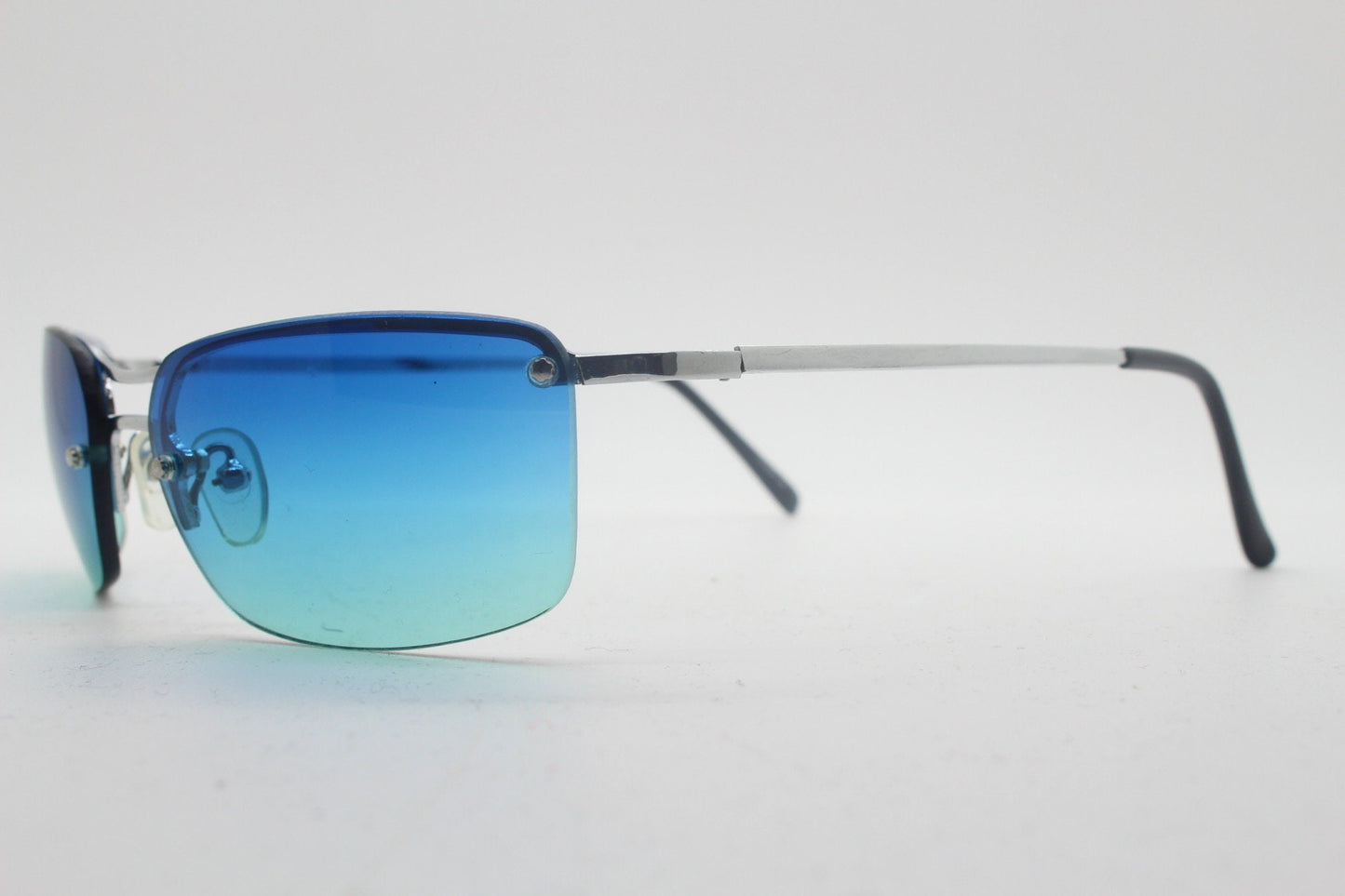 Y2K vintage visor sunglasses. Half frame wraparound shield design with light tone graduating turquoise to aquamarine lens. 2000's. 90s. NOS