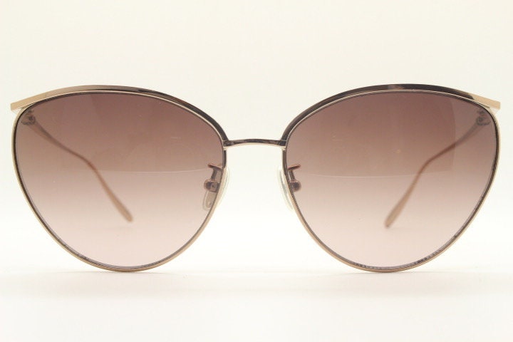 Carolina Herrera minimal cat eye sunglasses model SHN069 made in Italy. Women's gold titanium cateye frame with brown lenses. Vintage NOS
