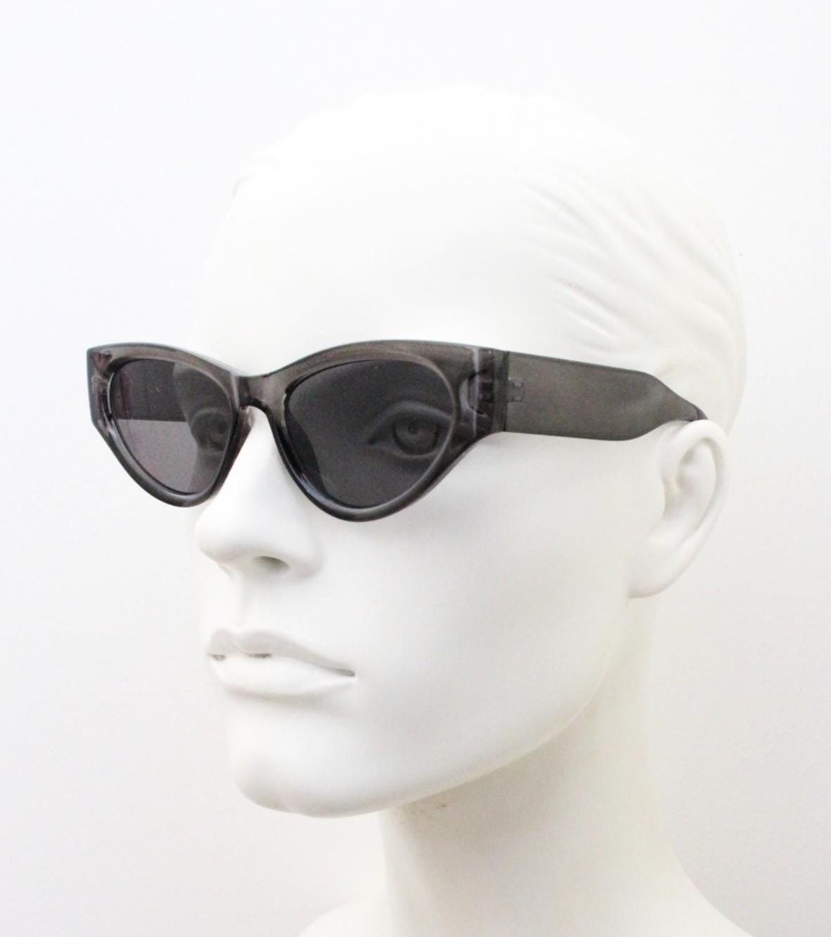 Thick cateye sunglasses with cropped sides and sharp outline. Womens 60s design chunky transparent grey frame and lenses. Y2k vintage