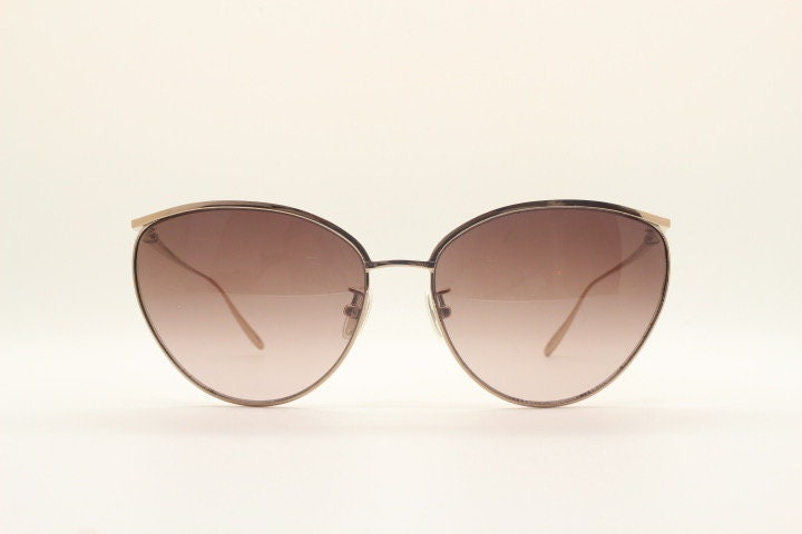 Carolina Herrera minimal cat eye sunglasses model SHN069 made in Italy. Women's gold titanium cateye frame with brown lenses. Vintage NOS