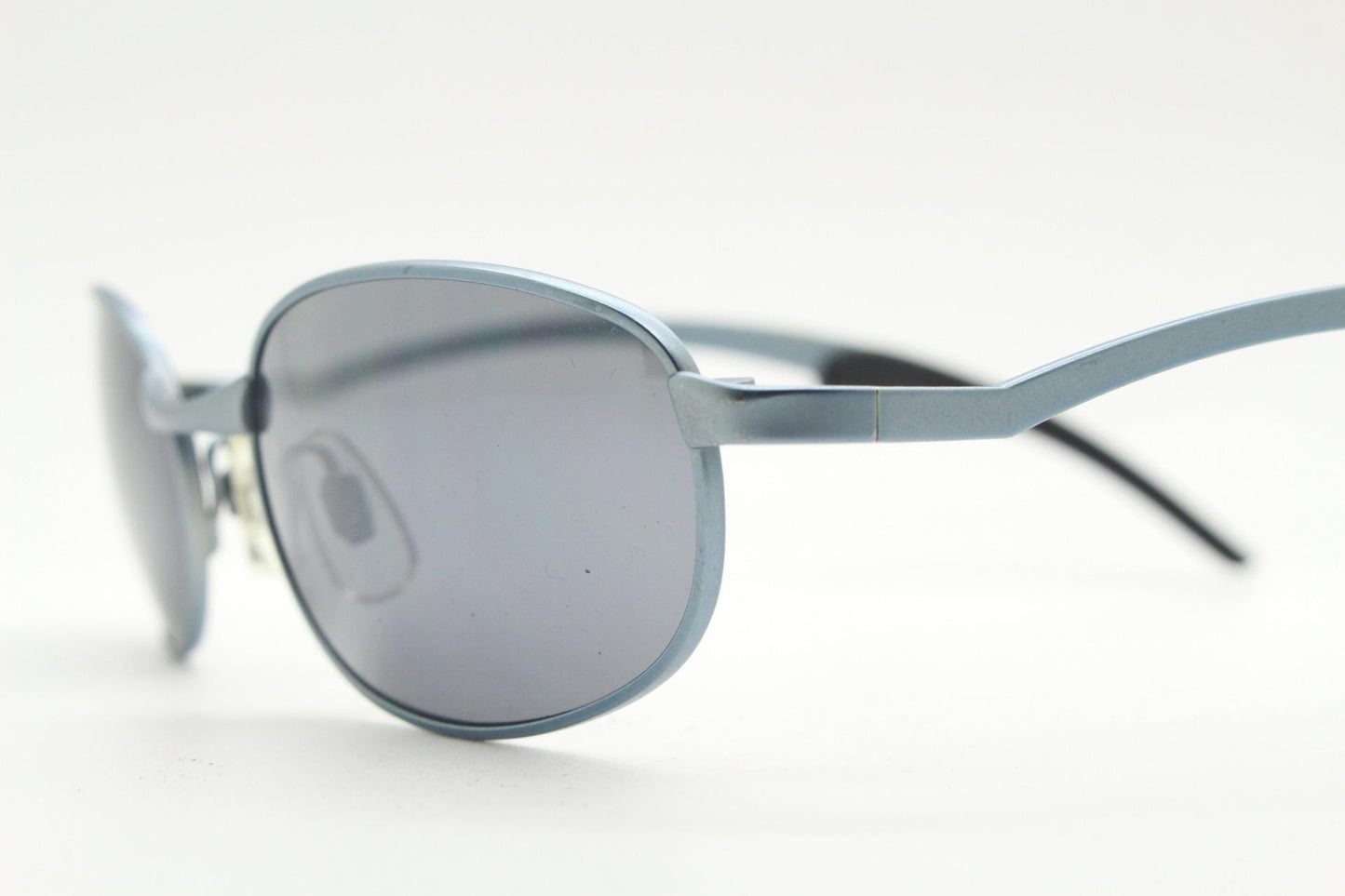 90s vintage oval small bug eye sunglasses. Curved blue satin finish solid metal frame with stylised arched arms and rubber ends. Unused NOS