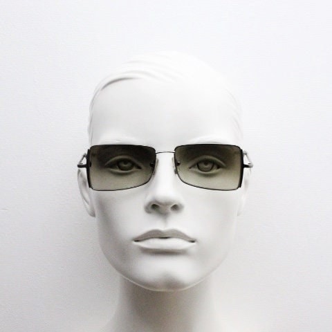 May include: A mannequin wearing a pair of black square-shaped sunglasses with brown tinted lenses.