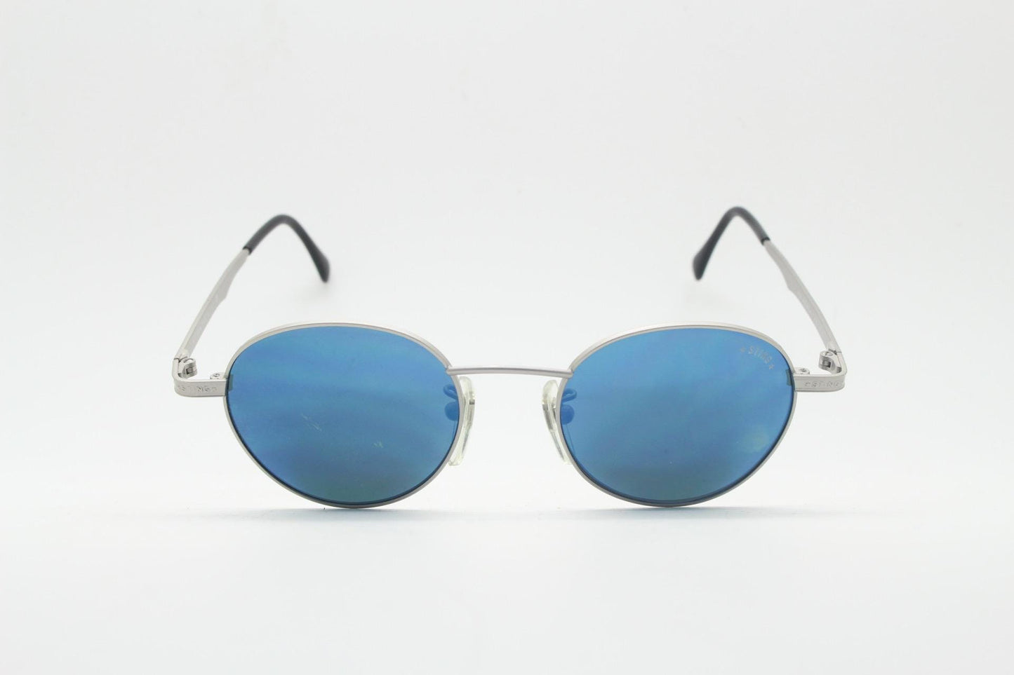 Sting 90s vintage oval sunglasses made in Italy. Minimal grey aluminium look in slightly small proportions with blue mirror lenses