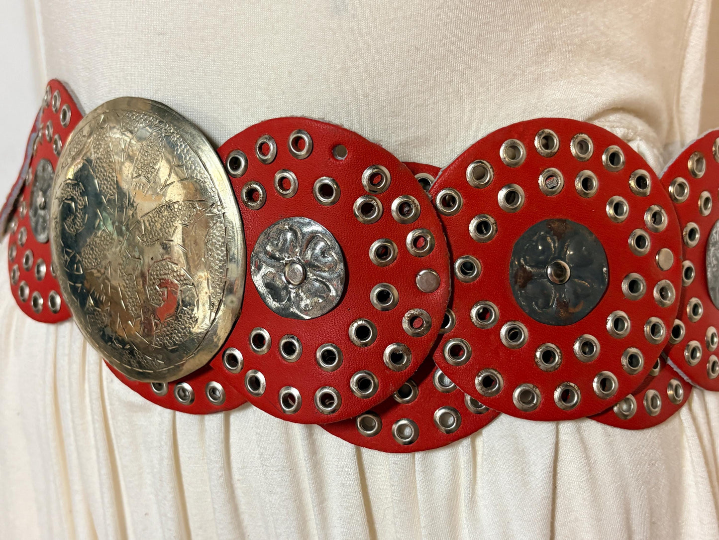 80s vintage womens huge red leather circles belt. Versatile statement piece with holed studs, metal discs and big 'shield' buckle. NOS
