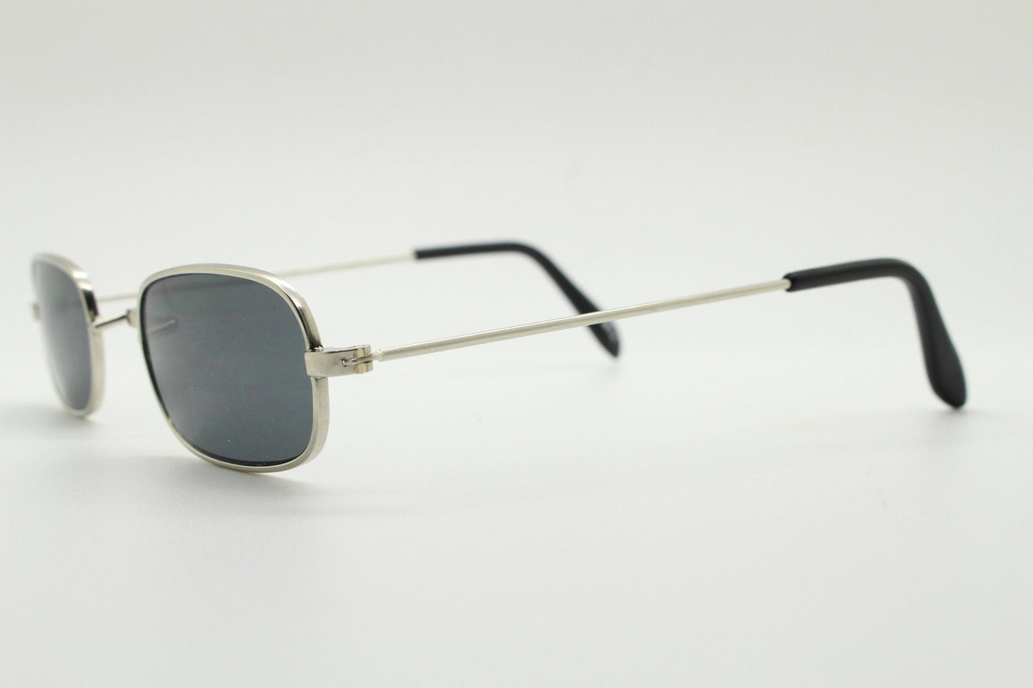 80s vintage rectangular low profile metal sunglasses. Minimal 60s mens mod design in silver chrome frame with grey lenses. NOS