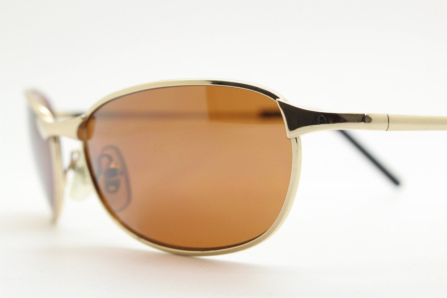90s vintage curved angular oval sunglasses. Solid metal small bug eye frame in gold chrome with mid tone brown lenses. 2000's. Y2K NOS