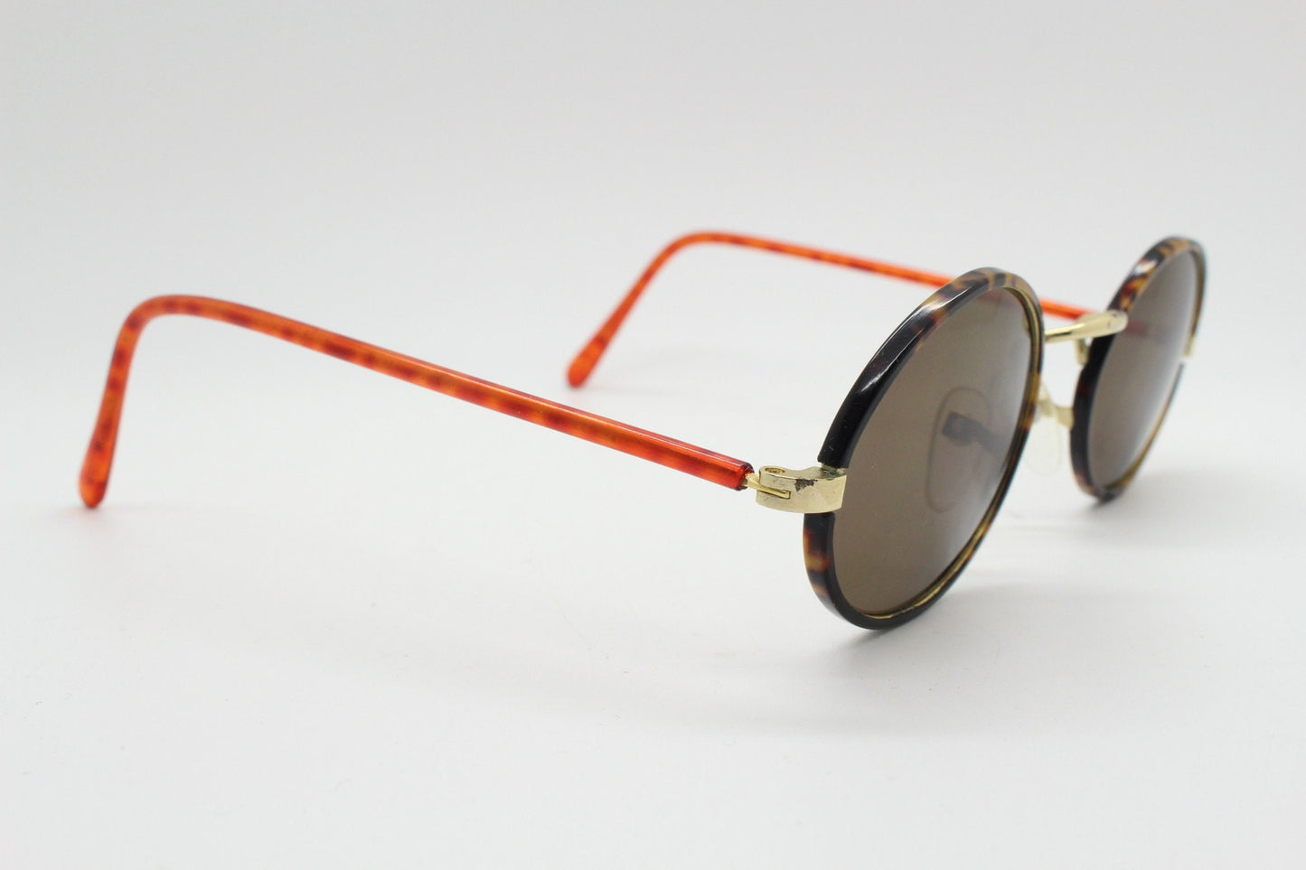 90s vintage oval sunglasses. Handsome honey tortoise and blazing amber arm combo on a slender metal frame. NOS