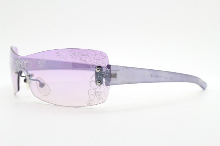 Y2K vintage visor sunglasses. Frameless 2000's purple wraparound mini mask shield design with light tone mono lens and flower print. 00s NOS