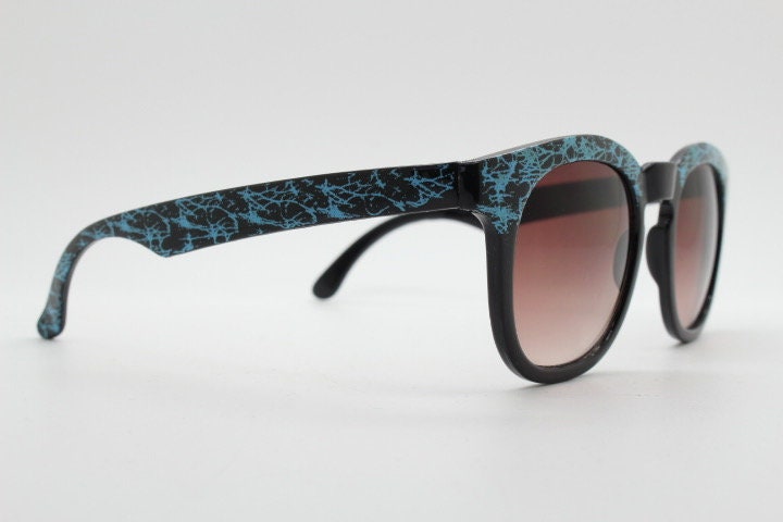 80s vintage rounded wayfarer design sunglasses. Abstract patterned blue brow and arms on a black frame with graduating  lenses. Unused NOS
