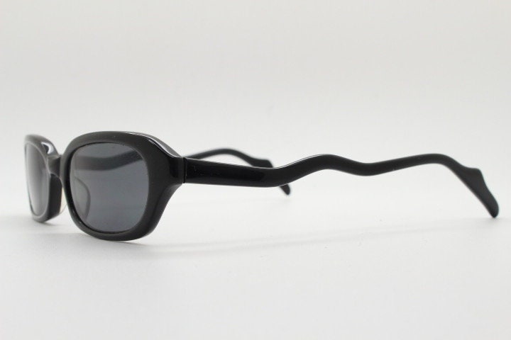90s vintage rectangular minimal cat eye sunglasses. Small black acetate low profile frame with extraordinary waved arms. Unused NOS