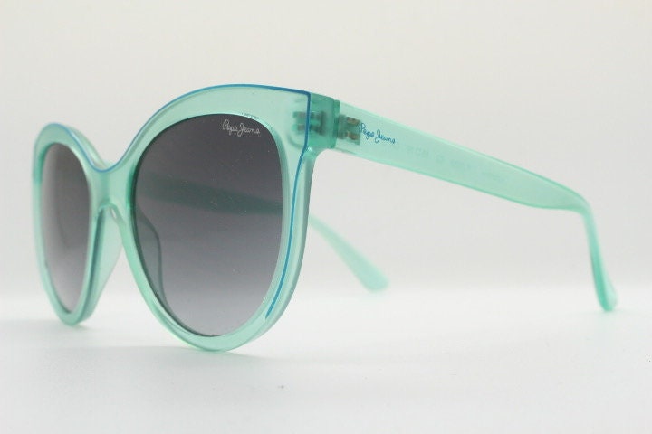 Pepe Jeans big cat eye sunglasses. Transparent chunky aquamarine frame with contrasting black graduating lenses. Womens vintage cateye