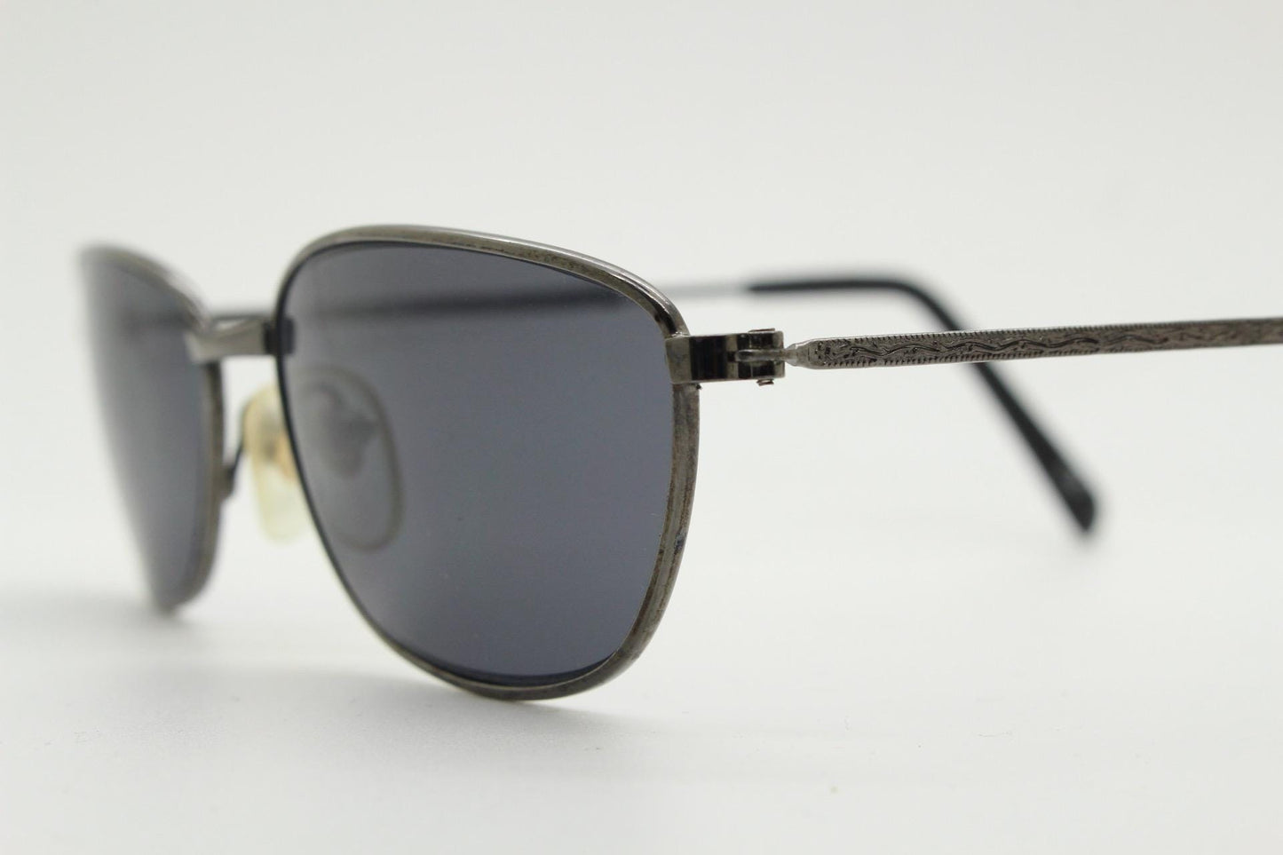 90s vintage angular pointed sunglasses. Minimal grey chrome metal frame with embossed patterned arms. Subtle cat eye. NOS