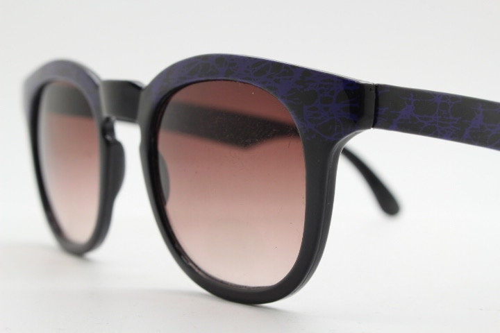 80s vintage rounded wayfarer design sunglasses. Abstract patterned purple brow and arms on a black frame with graduating  lenses. Unused NOS
