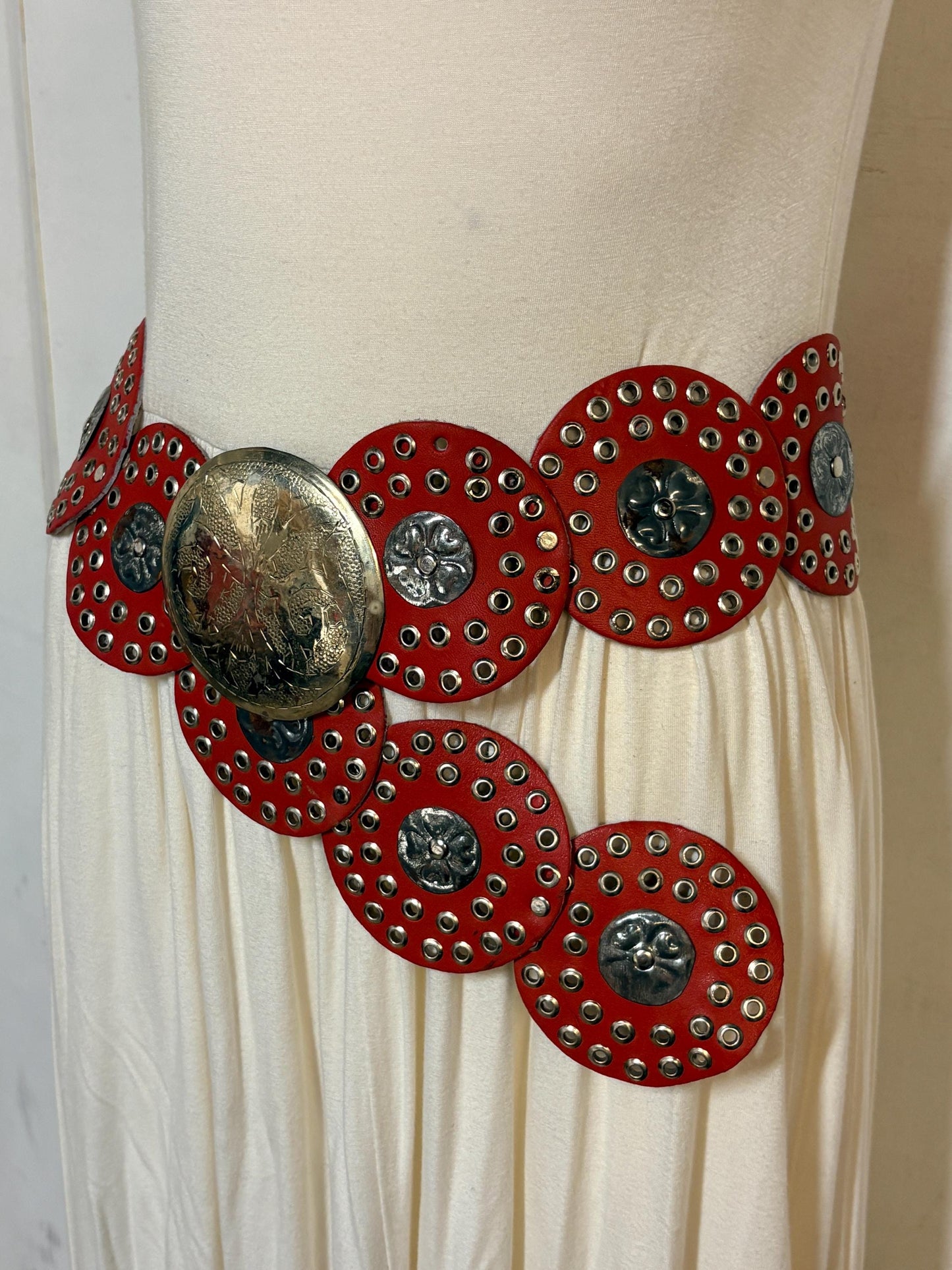 80s vintage womens huge red leather circles belt. Versatile statement piece with holed studs, metal discs and big 'shield' buckle. NOS