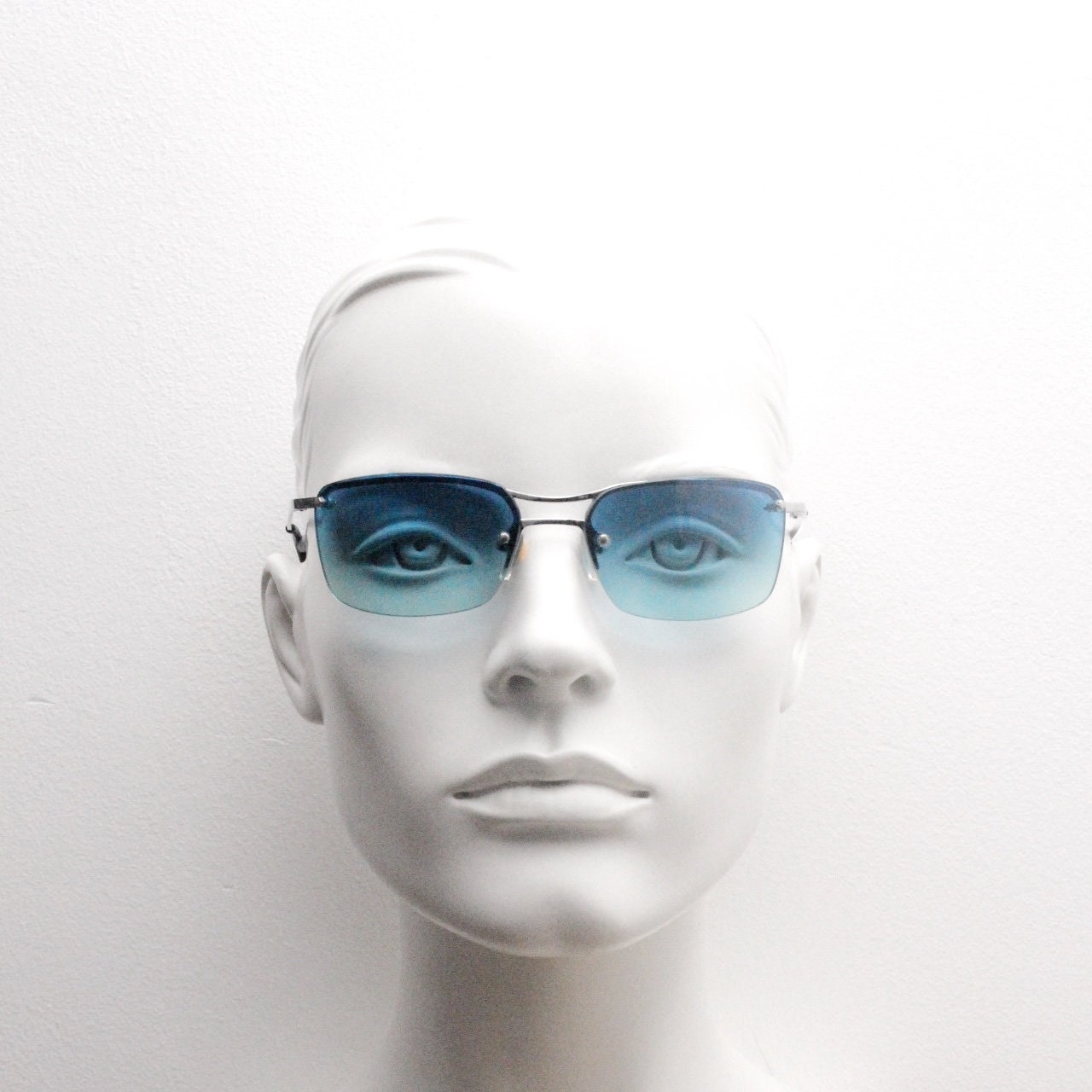 Y2K vintage visor sunglasses. Half frame wraparound shield design with light tone graduating turquoise to aquamarine lens. 2000's. 90s. NOS