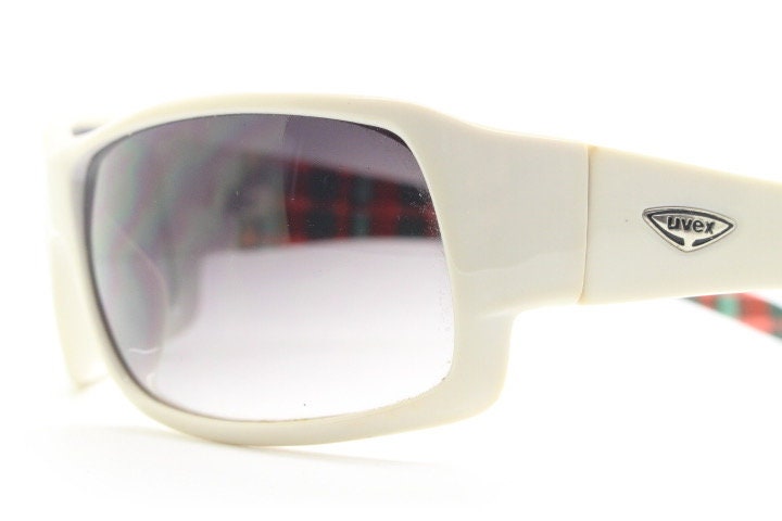Uvex Y2k vintage wrap around bug eye sunglasses. Curving white sports shield frame with black lenses and tartan interior. Rave 2000s. NOS