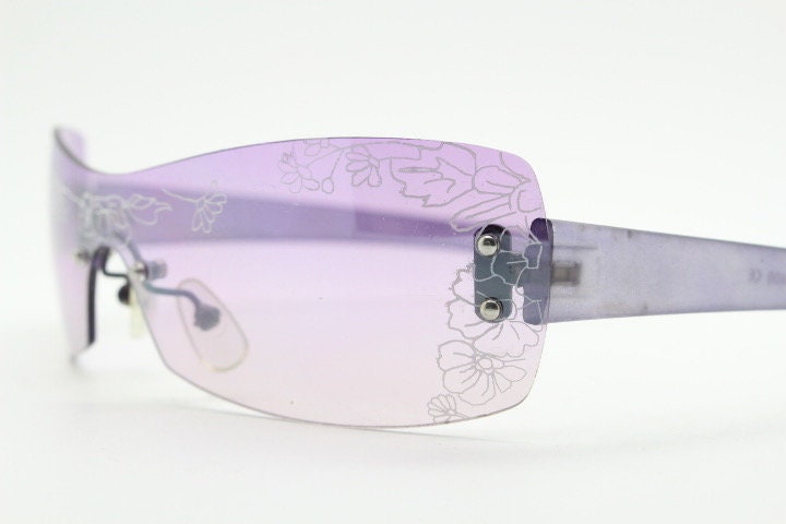 Y2K vintage visor sunglasses. Frameless 2000's purple wraparound mini mask shield design with light tone mono lens and flower print. 00s NOS