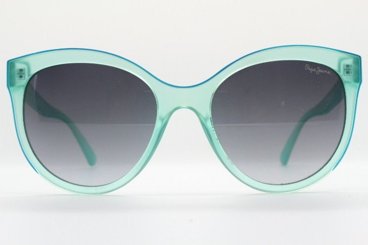 Pepe Jeans big cat eye sunglasses. Transparent chunky aquamarine frame with contrasting black graduating lenses. Womens vintage cateye