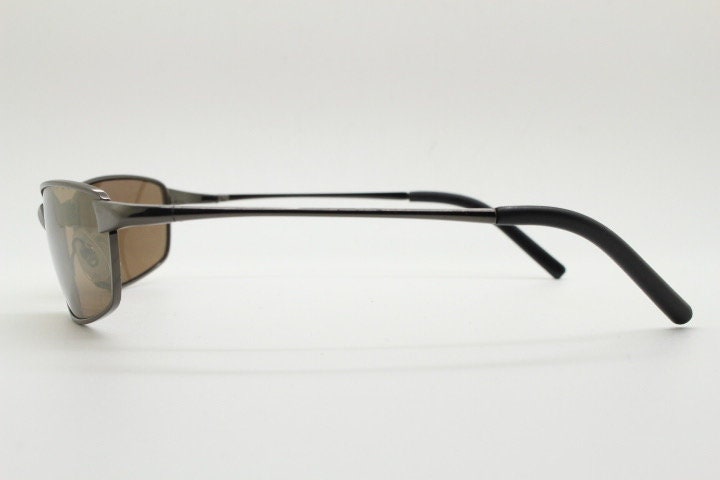 90s vintage curved rectangular sunglasses. Solid metal low profile frame in brown chrome with slightly mirrored lenses. 2000's. Y2K NOS