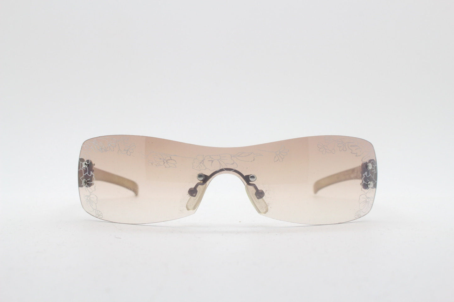 Y2K vintage visor sunglasses. Frameless 2000's wraparound mini mask shield design with light tone mono lens and flower print. 00s NOS