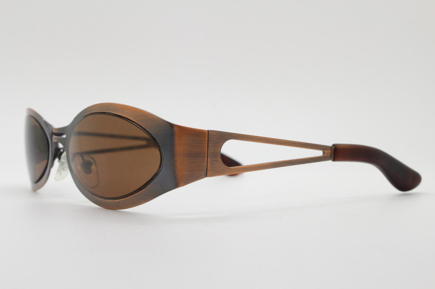 2000s vintage wraparound angular sunglasses. brushed copper finish flat curved metal frame with cut out arms. 90s. Y2K unused NOS