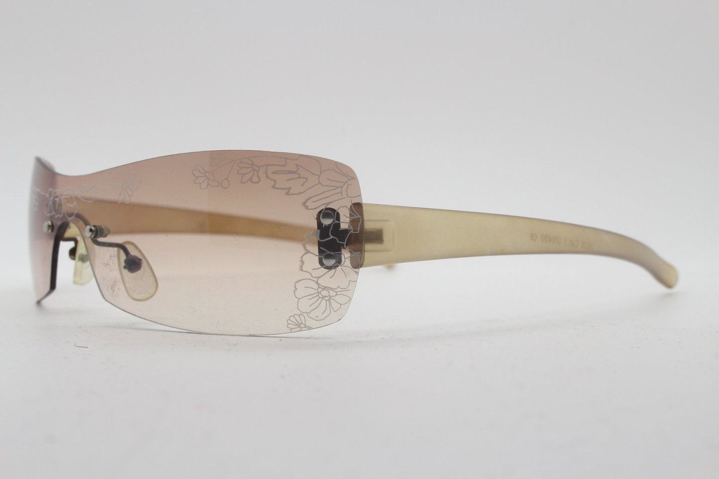 Y2K vintage visor sunglasses. Frameless 2000's wraparound mini mask shield design with light tone mono lens and flower print. 00s NOS