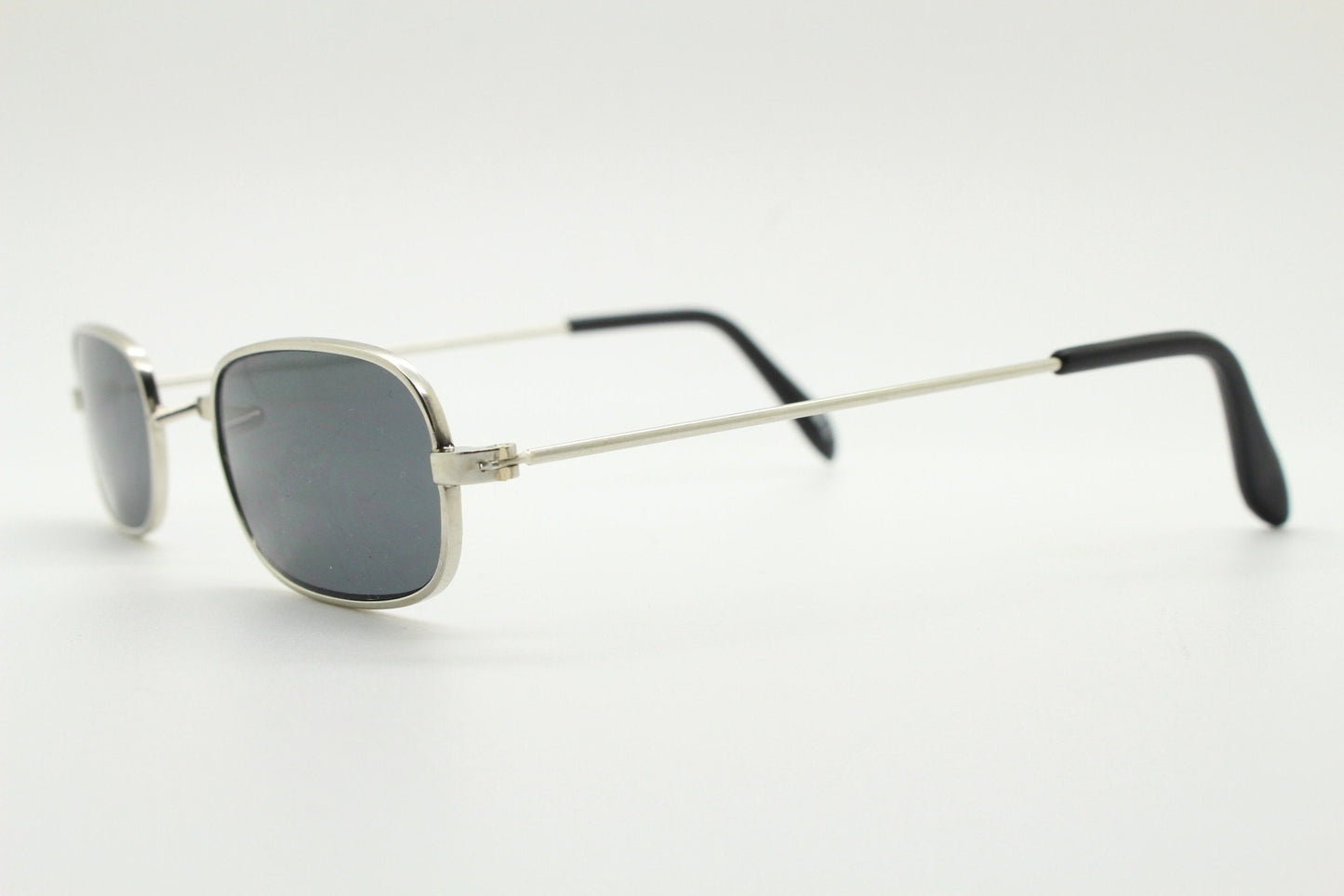 80s vintage rectangular low profile metal sunglasses. Minimal 60s mens mod design in silver chrome frame with grey lenses. NOS