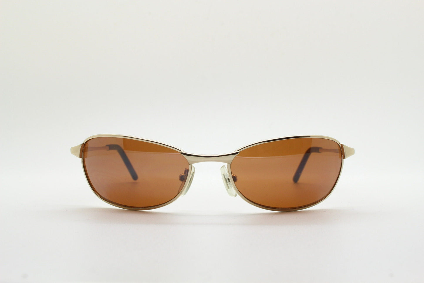 90s vintage curved angular oval sunglasses. Solid metal small bug eye frame in gold chrome with mid tone brown lenses. 2000's. Y2K NOS