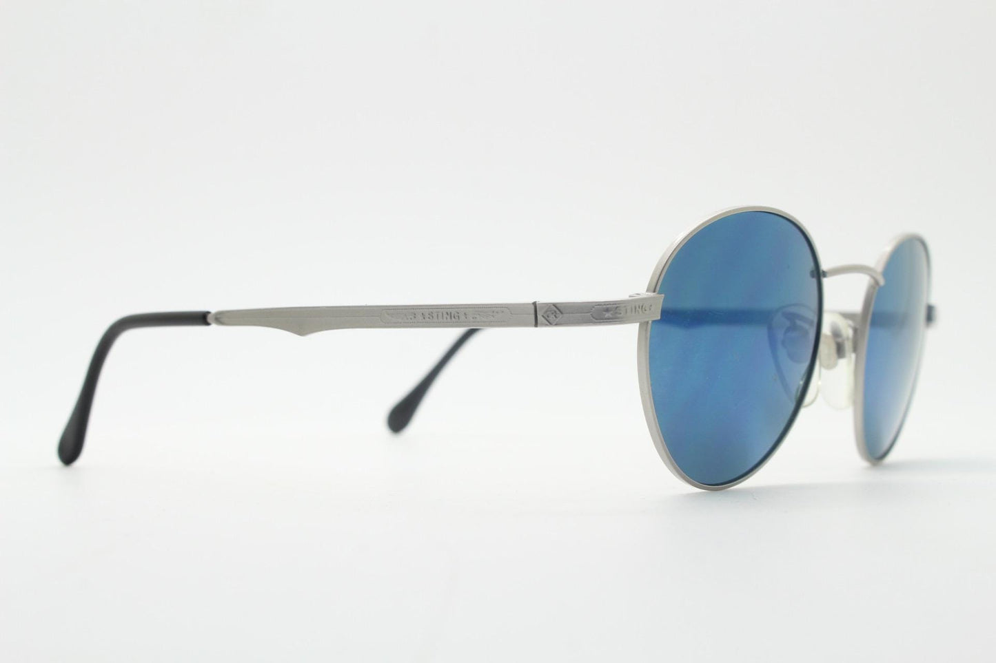 Sting 90s vintage oval sunglasses made in Italy. Minimal grey aluminium look in slightly small proportions with blue mirror lenses