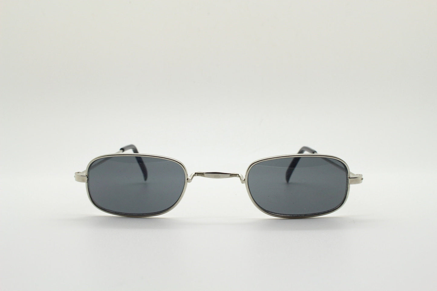 80s vintage rectangular low profile metal sunglasses. Minimal 60s mens mod design in silver chrome frame with grey lenses. NOS
