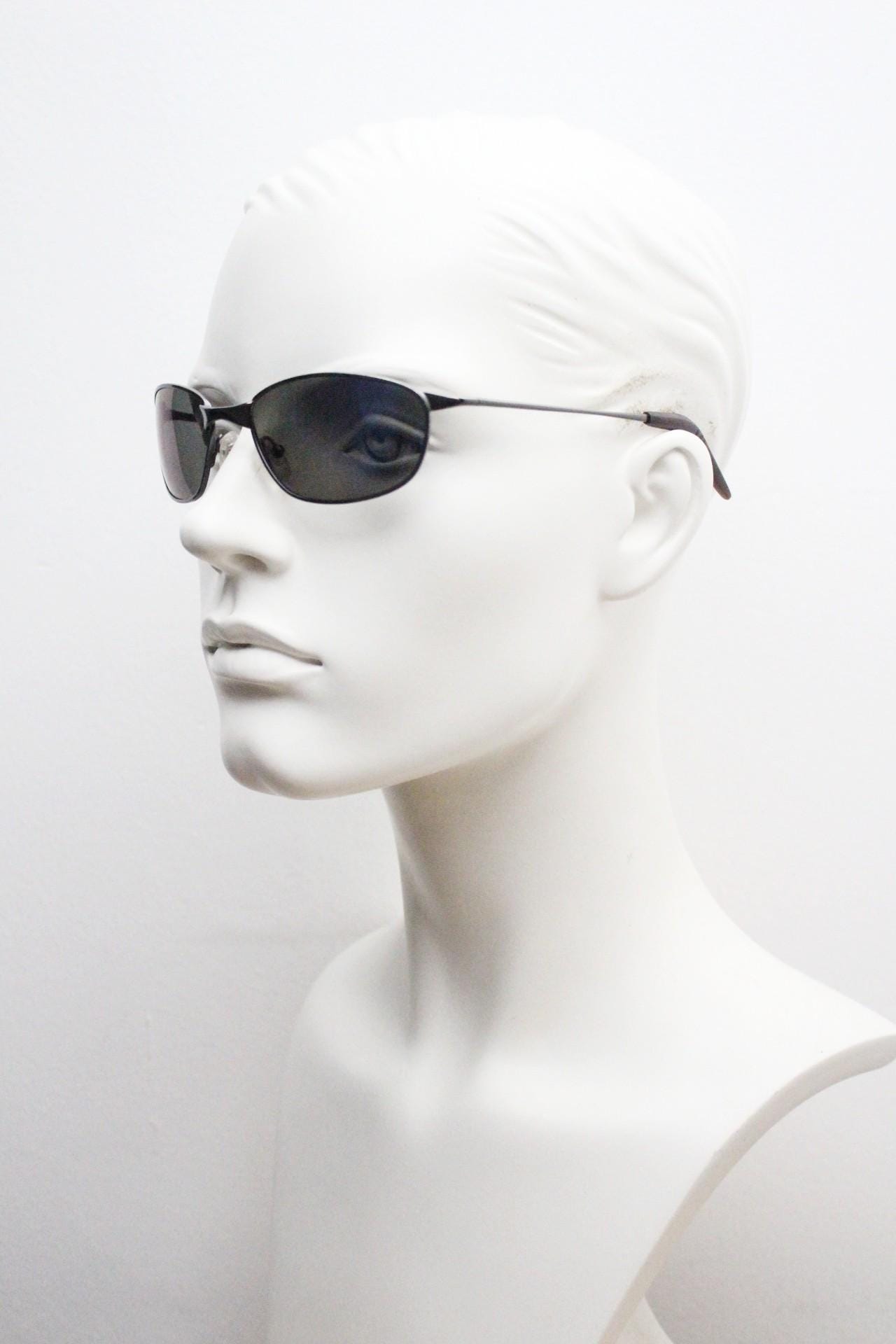 90s vintage curved oval sunglasses. Solid metal low profile frame in grey chrome with slightly mirrored dark lenses. 2000's. Y2K NOS