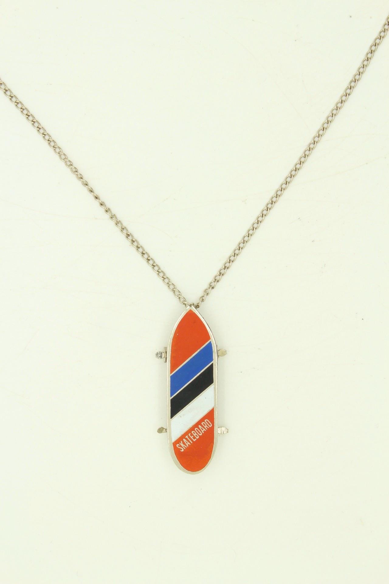 80s vintage skateboard pendant necklace. Metal chrome with enamelled red, blue and white colour stripes. Charming authentic design. NOS