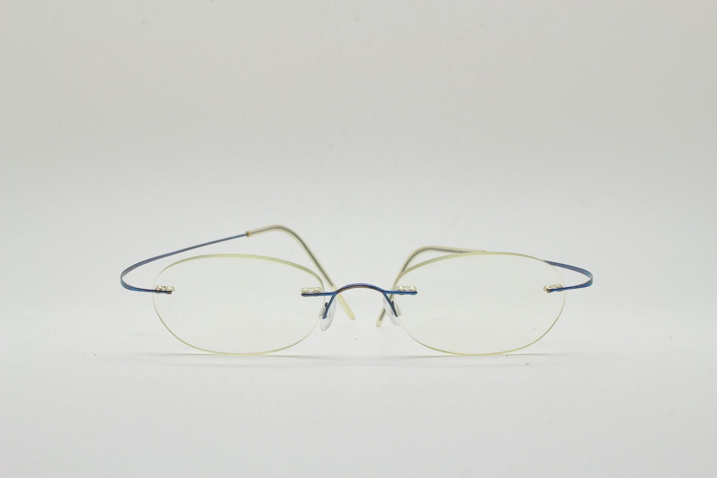 Frameless vintage oval eye glasses. Extremely minimal lightweight blue titanium optical frame with springy hingeless arms. 2000s