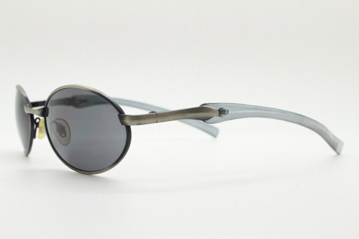 90s vintage small oval  bug eye sunglasses. Brushed bronze finish frame with transparent grey arms. Y2K. 2000s. Unworn NOS