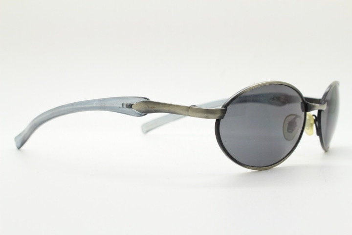 90s vintage small oval  bug eye sunglasses. Brushed bronze finish frame with transparent grey arms. Y2K. 2000s. Unworn NOS
