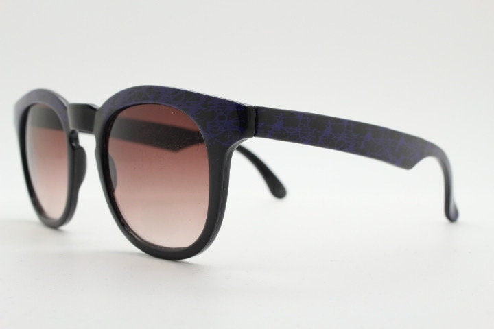 80s vintage rounded wayfarer design sunglasses. Abstract patterned purple brow and arms on a black frame with graduating  lenses. Unused NOS